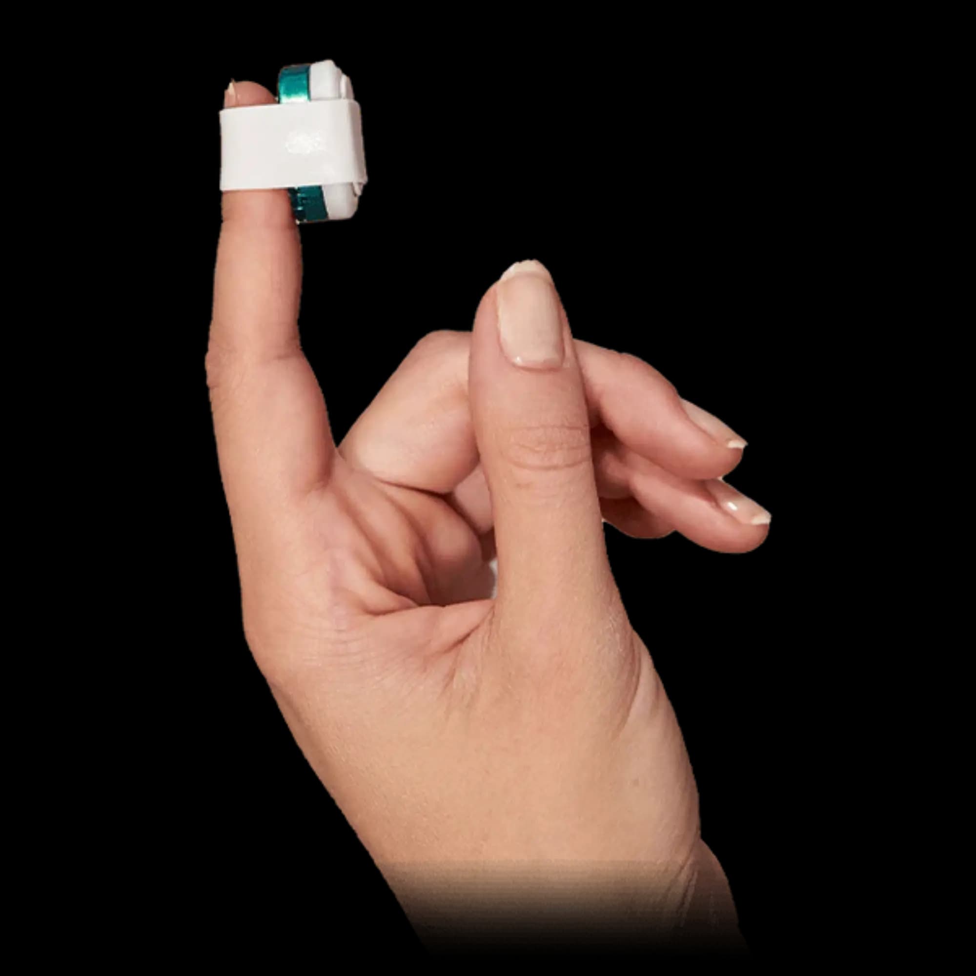 A hand resting on bedding at night, the sensor on the index fingertip under its white wrap